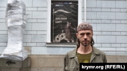 Рустем Скибін біля Київської картинної галереї перед відкриттям виставки, про яку повідомляє оголошення на стіні будівлі