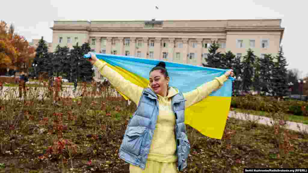 Місцева жителька з національним прапором України перед будівлею ОДА в Херсоні, 13 листопада 2022 року