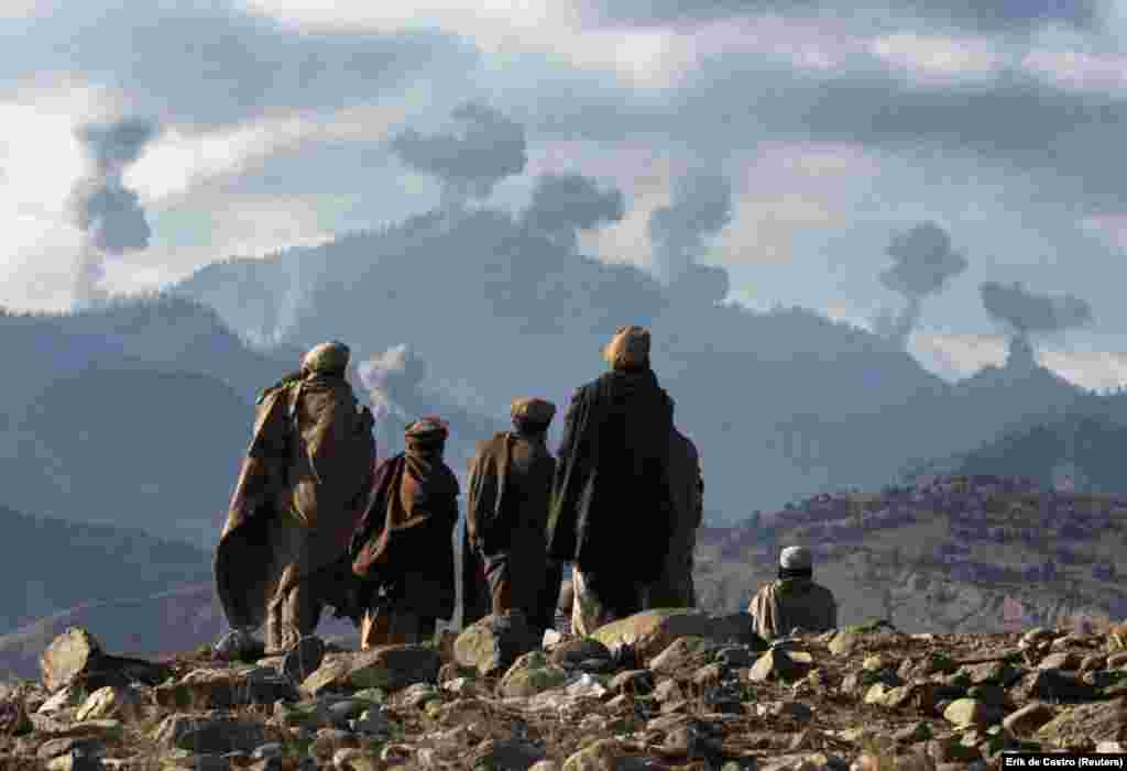 Афганські бойовики спостерігають за вибухами американських бомб в гірському комплексі Тора-Бора в Афганістані у грудні 2001 року. Коли Сполучені Штати вторглися в Афганістан після терактів 11 вересня, масований повітряний напад за підтримки наземних винищувачів був здійснений на серію гірських печер, відомих як Тора-Бора. Вважалося, що бін Ладен і його бійці &laquo;Аль-Каїди&raquo; ховалися в Тора-Бора в тих горах, перш ніж він втік до Пакистану