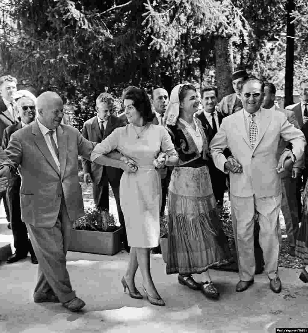 Радянський лідер Микита Хрущов (ліворуч) і Тіто (праворуч) танцюють із місцевими жителями в місті Цетинє, Чорногорія, в 1963 році. Югославія в той час планувала отримати сотні мільйонів доларів у вигляді позик від західних країн і Радянського Союзу. Великі позики забезпечили б помітний, але короткочасний стрибок якості життя в Югославії