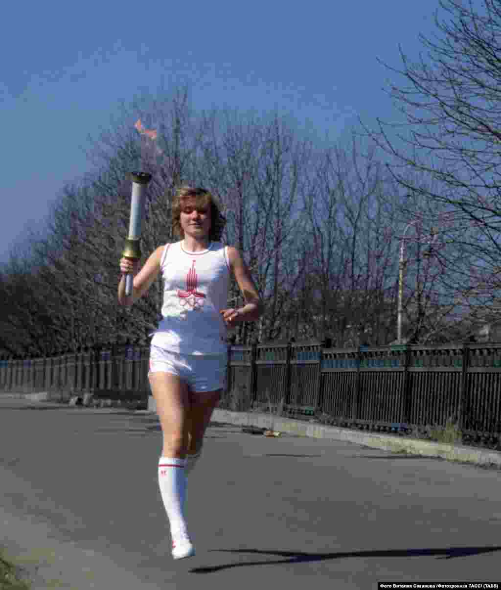Жінка біжить з олімпійським факелом перед відкриттям Ігор