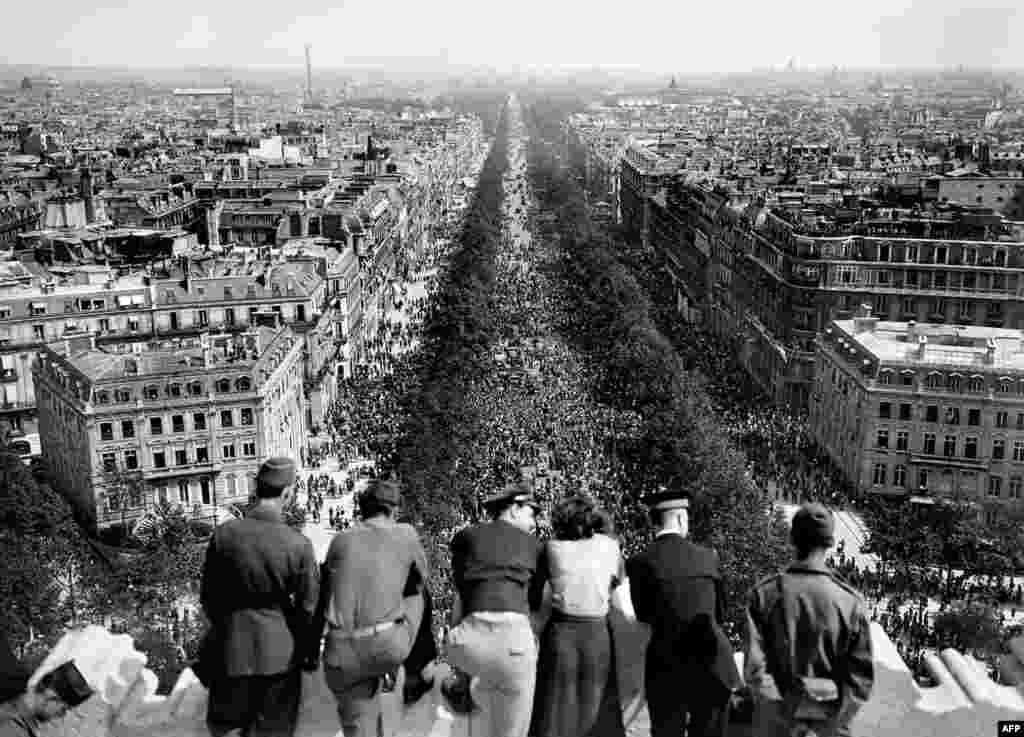 Люди спостерігають за юрбою, яка збирається біля Тріумфальної арки в Парижі, 8 травня 1945 року