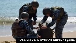 Українські військові знешкоджують морську міну, викинуту на берег штормом, під час масштабного вторгнення Росії в Україну, 2022 рік